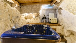 A stone-walled room with a wooden ceiling, a blue hot tub, and a chair. - Villa Strnj (Zivogosce)