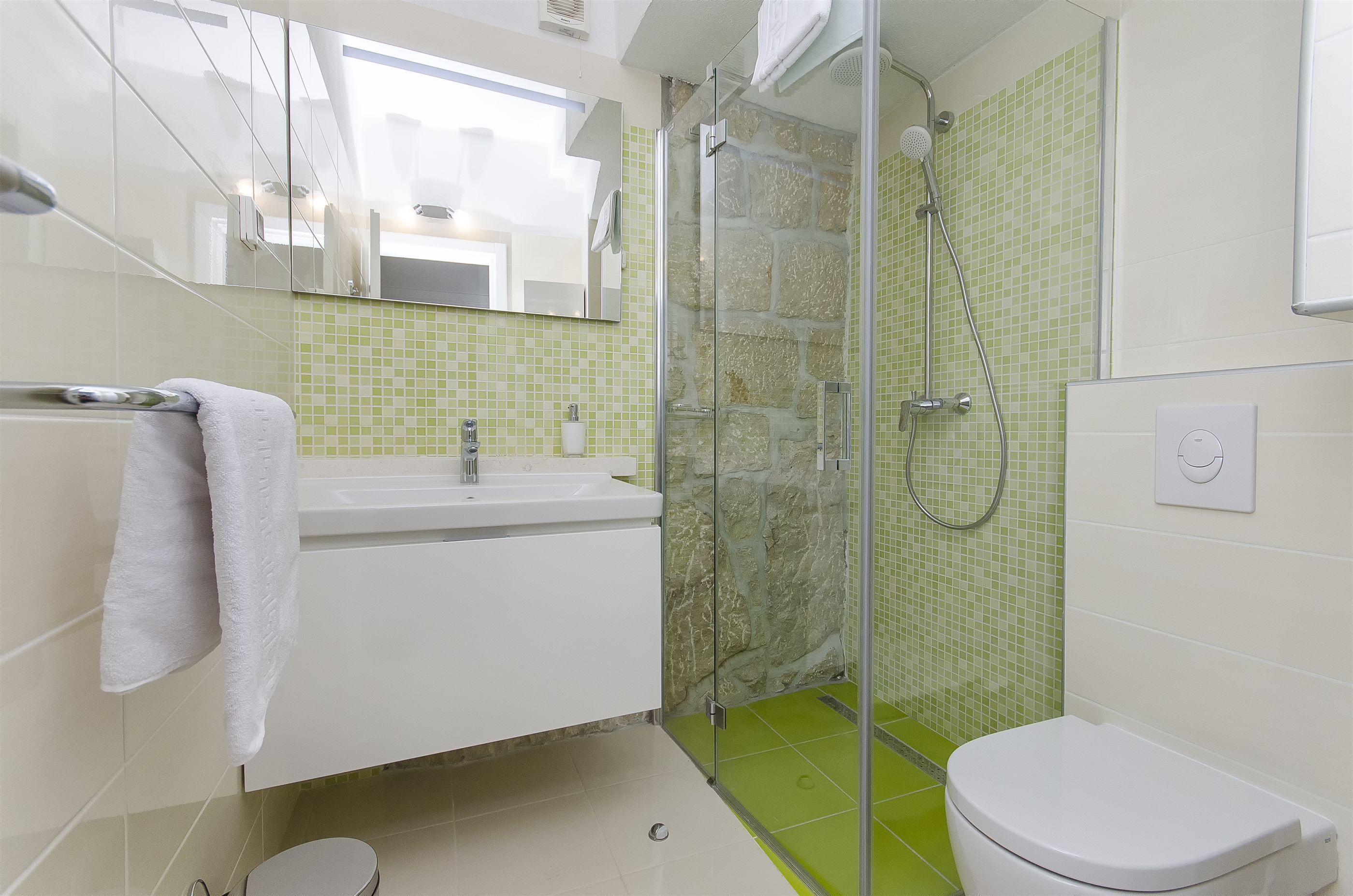 Un bany amb plat de dutxa de vidre, un lavabo blanc i un vàter.