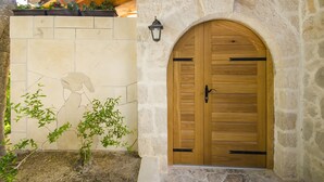 A stone wall with a wooden door and a small plant. - Villa Strnj (Zivogosce)