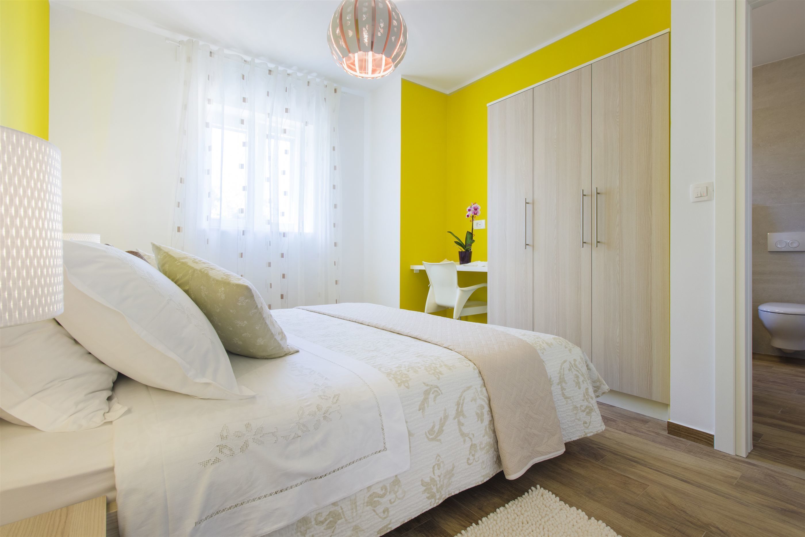 Een slaapkamer met een bed, bureau en een kledingkast.