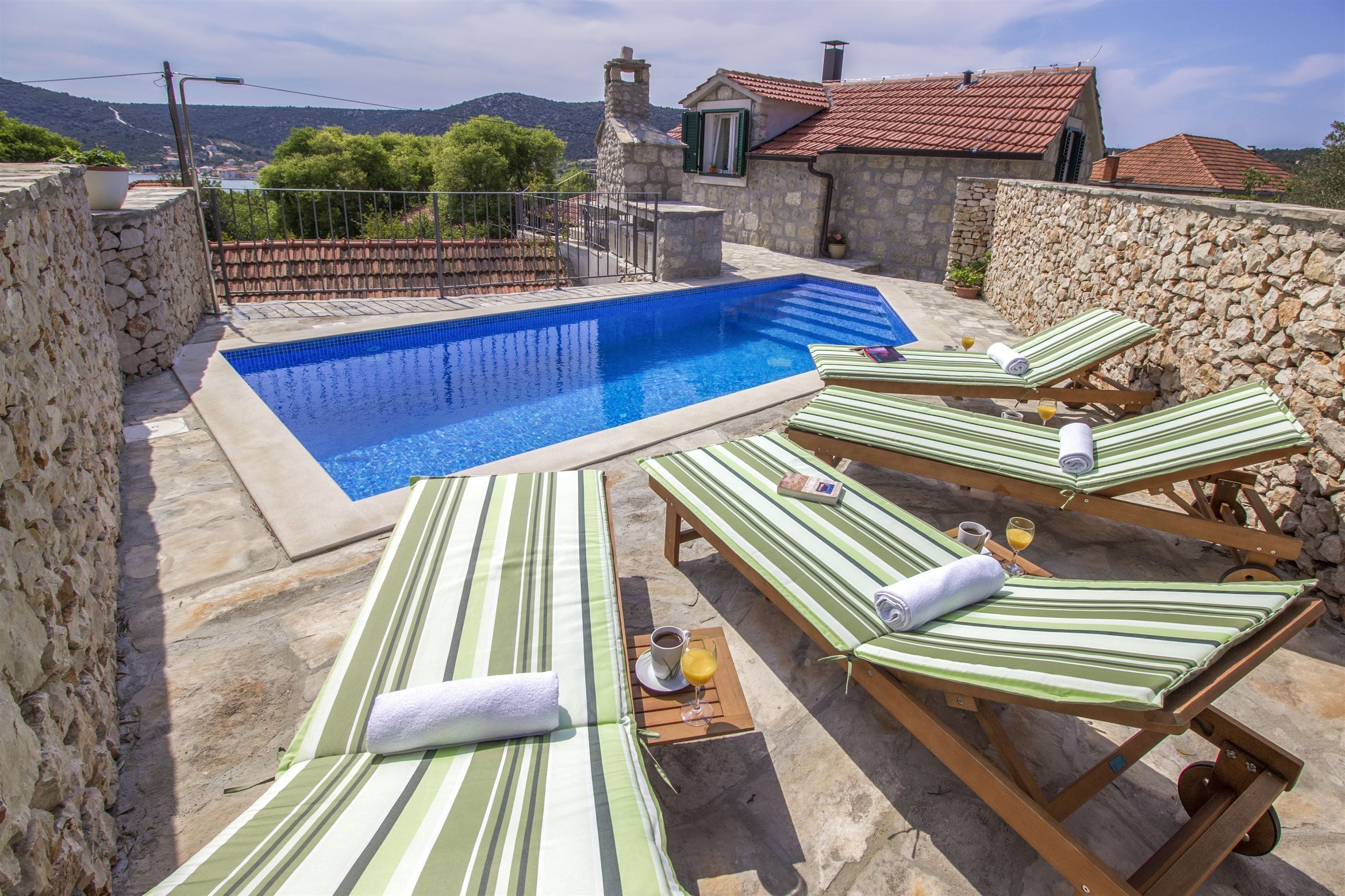 Un espace piscine avec des chaises longues et un mur en pierre.
