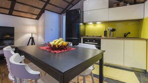 A modern kitchen with a black refrigerator, white cabinets, and a yellow backsplash. - Villa Burica (Vinisce)