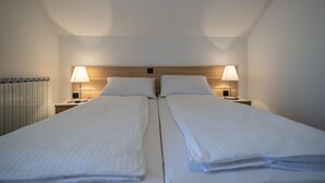 A hotel room with two single beds, each with a nightstand and a lamp. - Apartments and Room Robert (Korenica)