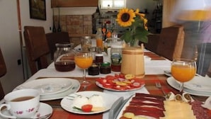 A breakfast setting with plates of food, a coffee cup, and a vase with a sunflower. - Apartments and Room Robert (Korenica)