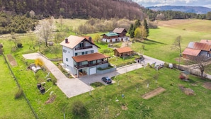 A rural house with a large front yard, a driveway, and a neighboring field. - Apartments and Room Robert (Korenica)