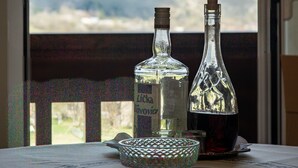 A table with two bottles and a glass bowl in a room with a mountain view. - Apartments and Room Robert (Korenica)