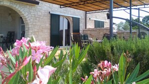 A covered outdoor area with stone walls, a pergola, and flowering plants. - Villa Aleksandra (Novigrad)