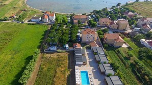 An aerial view of a coastal resort with multiple buildings, a swimming pool, and a beach. - Villa Rafajela (Privlaka)