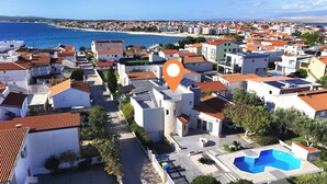 A coastal residential area with white buildings, red-tiled roofs, and a large blue swimming pool. - Villa Jelena Vir Near Beach (Liznjan)