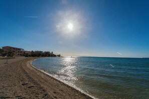 A beach with a clear sky, a building on the left, and a calm sea. - Villa Jelena Vir Near Beach (Liznjan)