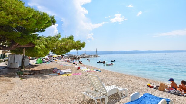 A beach with white lounge chairs, a clear sky, and calm water. - House La Casa Simone (Jesenice)