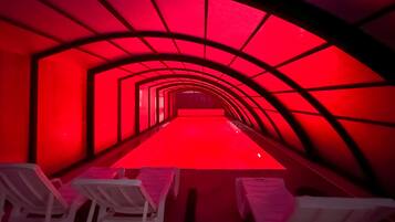 Una estructura en forma de túnel con iluminación roja y sillas blancas dispuestas a lo largo de los lados.