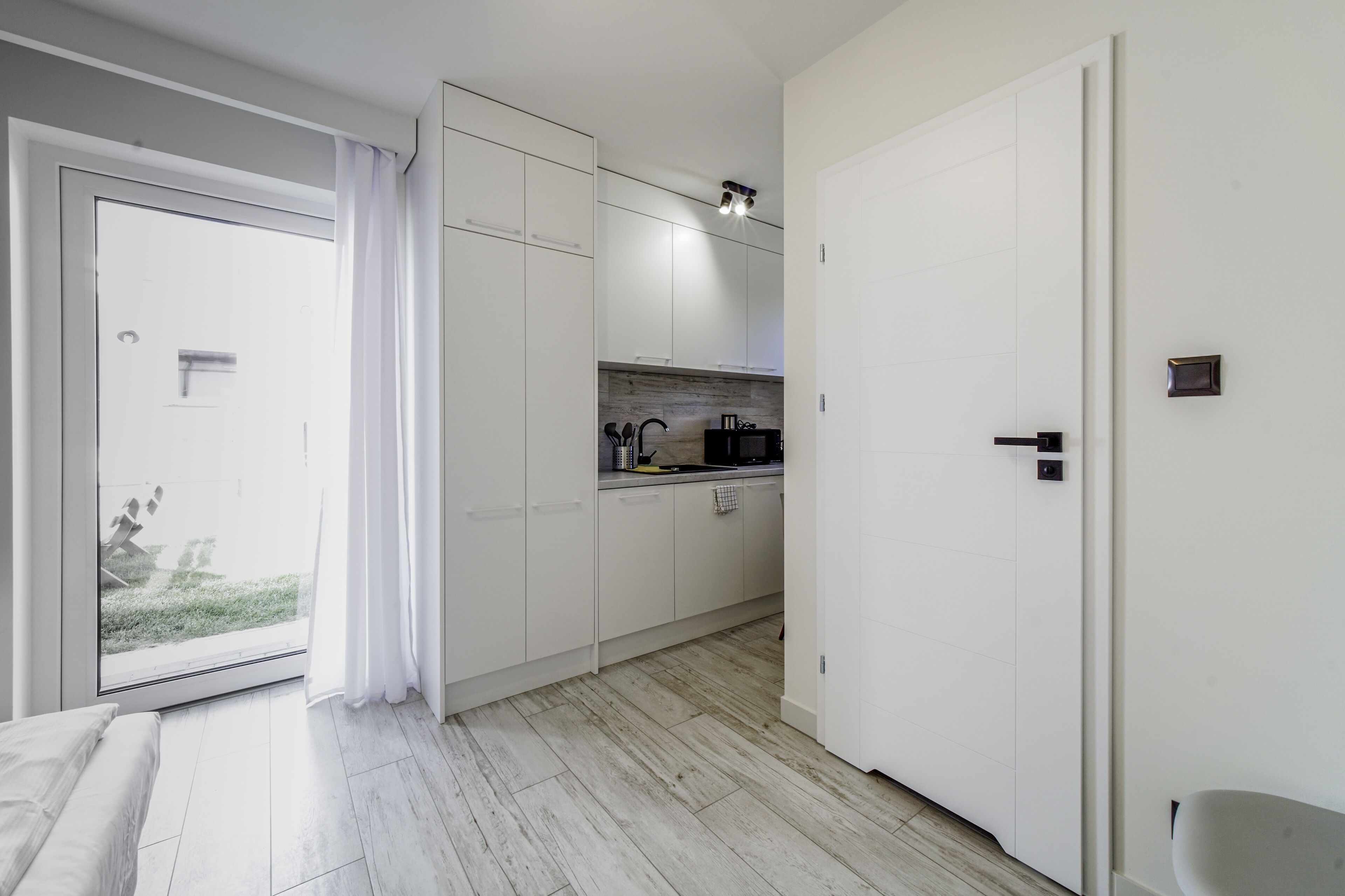 A modern kitchen with white cabinets, a countertop, and a sliding glass door leading to a balcony.