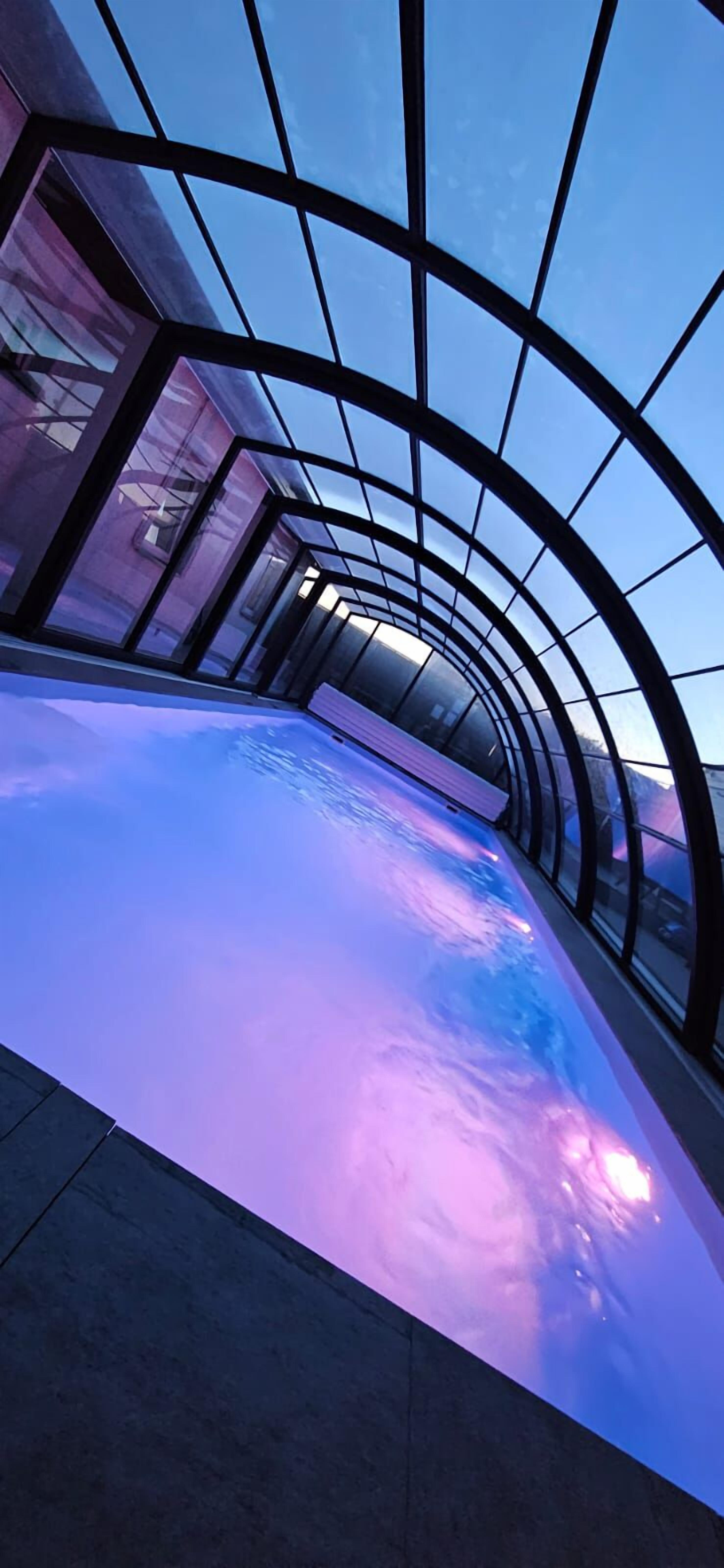 Un espacio interior moderno con techo de vidrio y suelo reflectante.