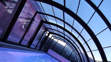 Un espace intérieur moderne doté d’un plafond en verre et d’un sol réfléchissant.