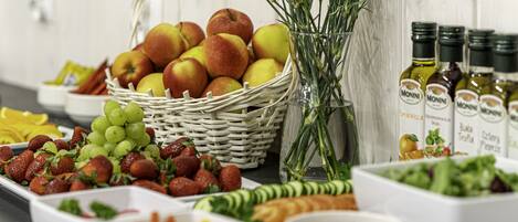 Une table de buffet proposant une variété d’aliments, notamment des fruits, des légumes et des sauces.