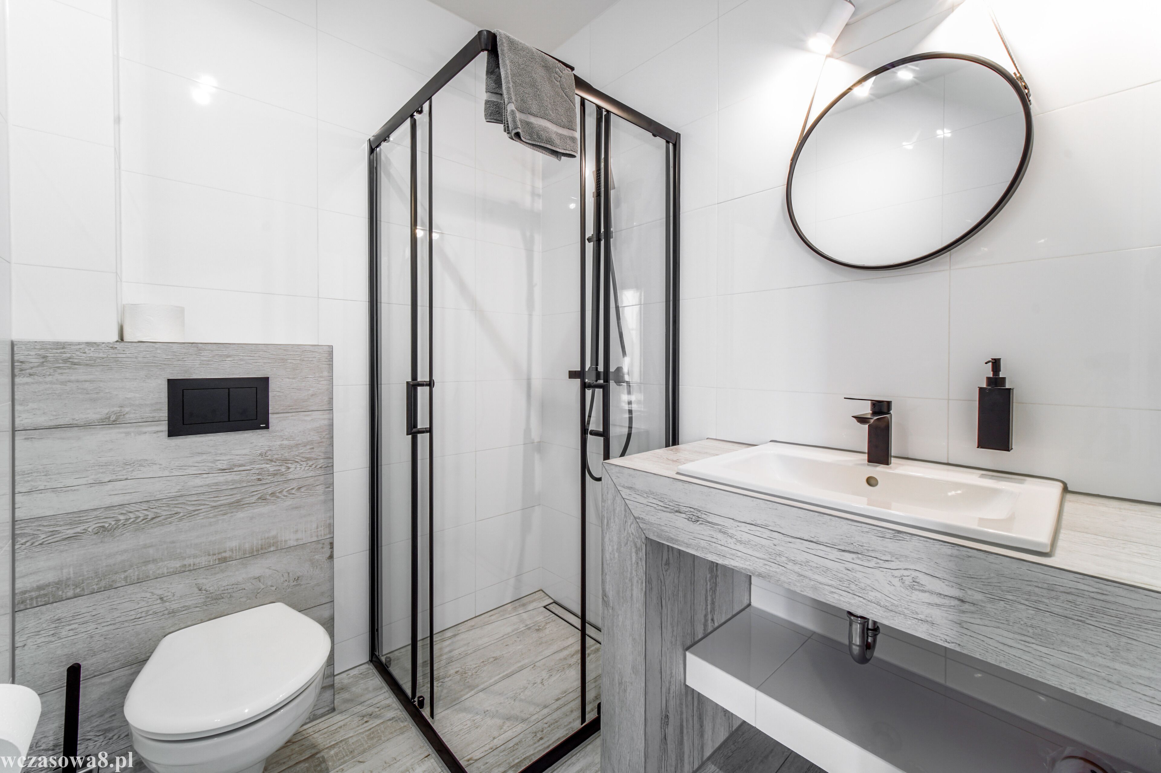 Un baño moderno con ducha de vidrio, inodoro blanco y tocador de mármol con lavabo.