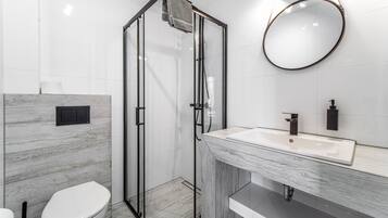 A modern bathroom with a glass-enclosed shower, a white toilet, and a marble vanity with a sink.
