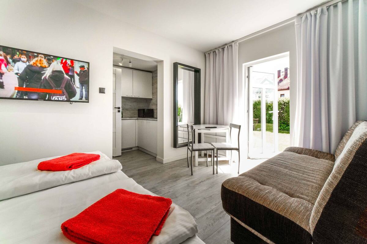 A hotel room with two beds, a TV, a dining area, and a view of the outdoors.
