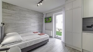 A modern bedroom with a bed, bedside table, and a TV mounted on the wall. - Wczasowa 8 Apartments Sarbinowo (Sarbinowo)