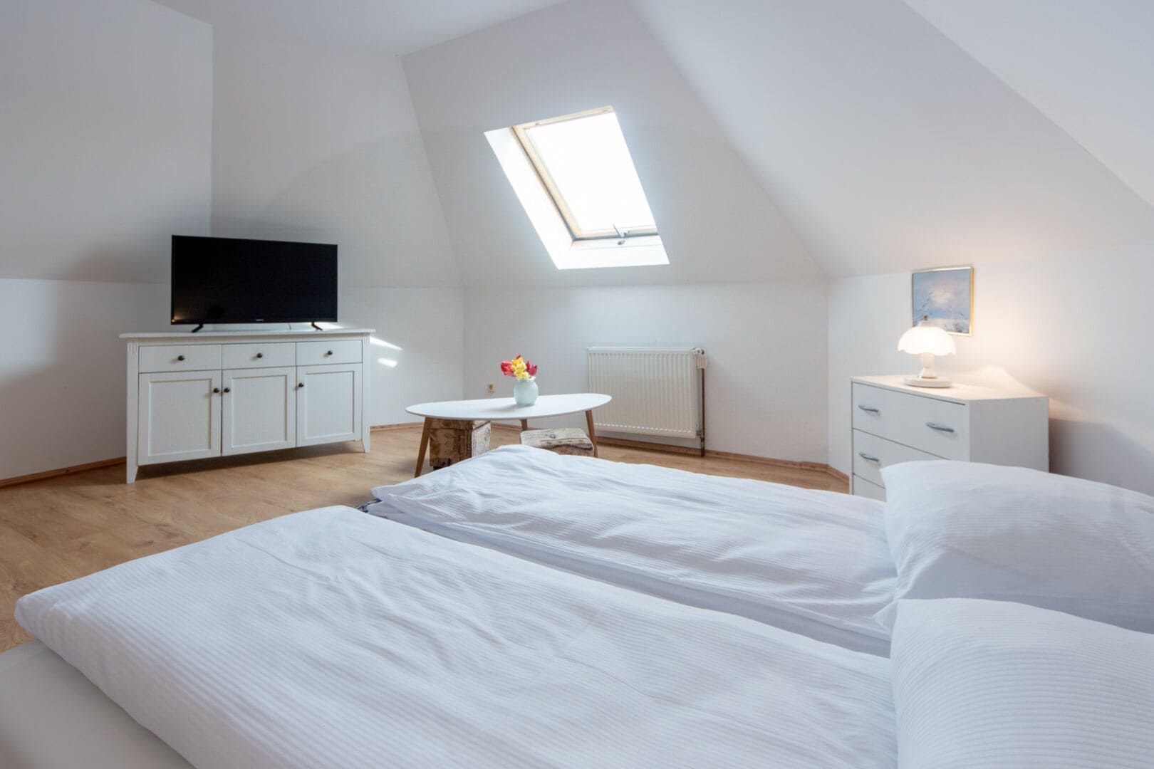 Une chambre avec deux lits, un bureau, une chaise, une télévision et une fenêtre de toit.