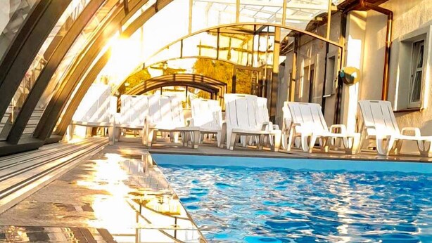 A swimming pool with lounge chairs and a glass ceiling structure. - Wczasowa 8 Apartments Sarbinowo (Sarbinowo)