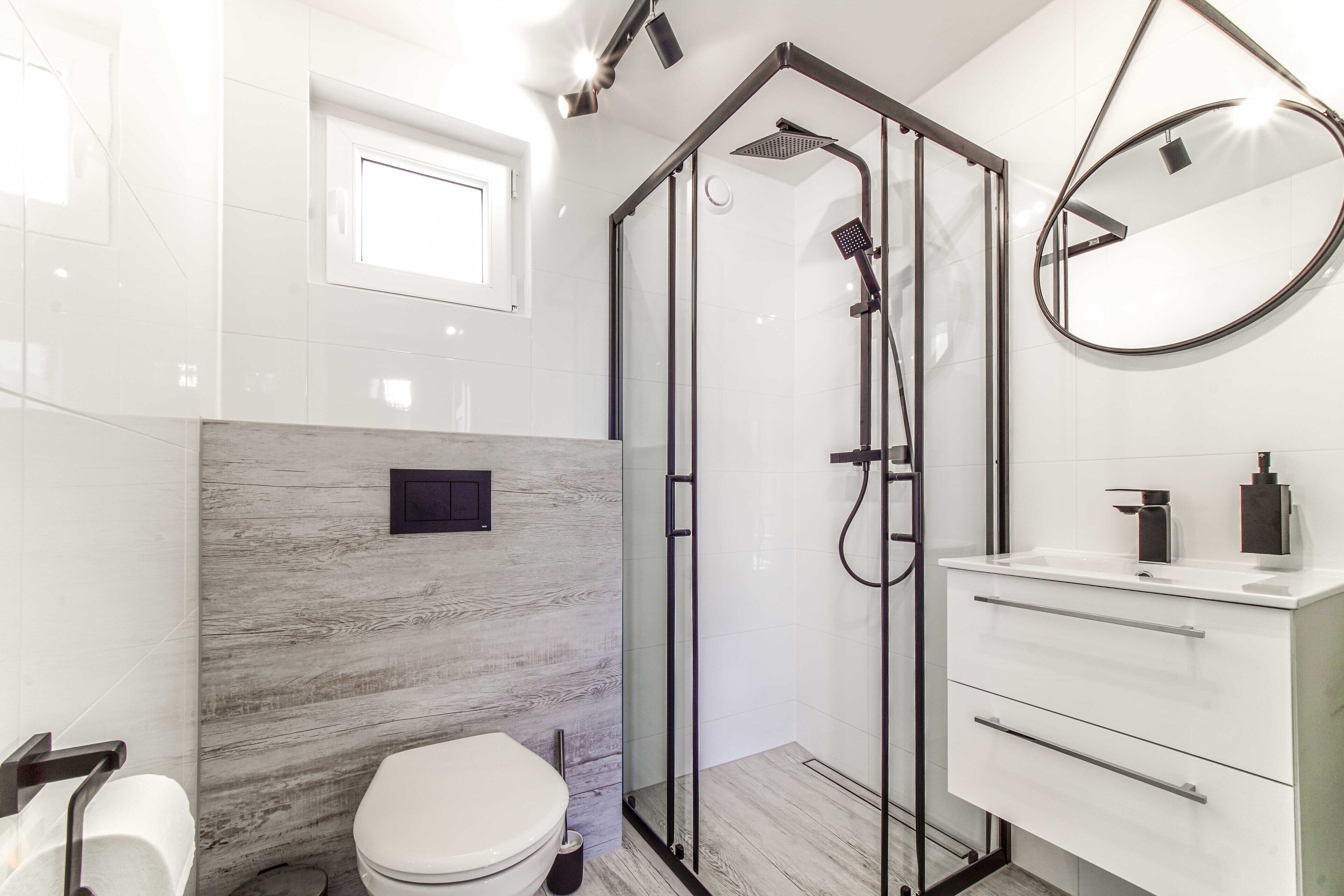 Un bagno moderno con doccia a vetro, un water bianco e un mobile vanitario con cassetti.