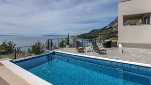 En swimmingpool med liggestole og havudsigt.