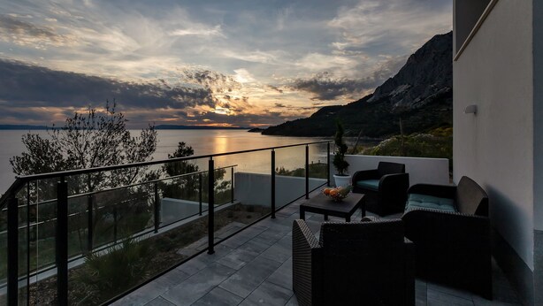 En balkon med udendørs møbler, havudsigt og et bjerglandskab.