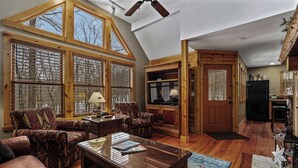 A spacious living room with large windows, a fireplace, and a cozy seating area.