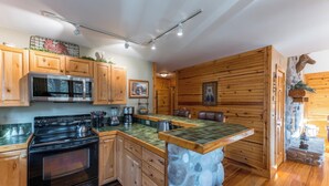 A kitchen with wooden cabinets, a stove, a microwave, and a stone island.