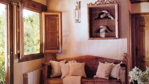 A rustic wooden interior with a wooden bench, a framed picture, and a window with a view of greenery. - Casa Rota (Arahuetes)
