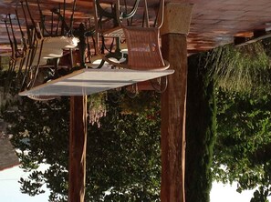A ceiling with hanging chairs and a table, surrounded by wooden beams and greenery.