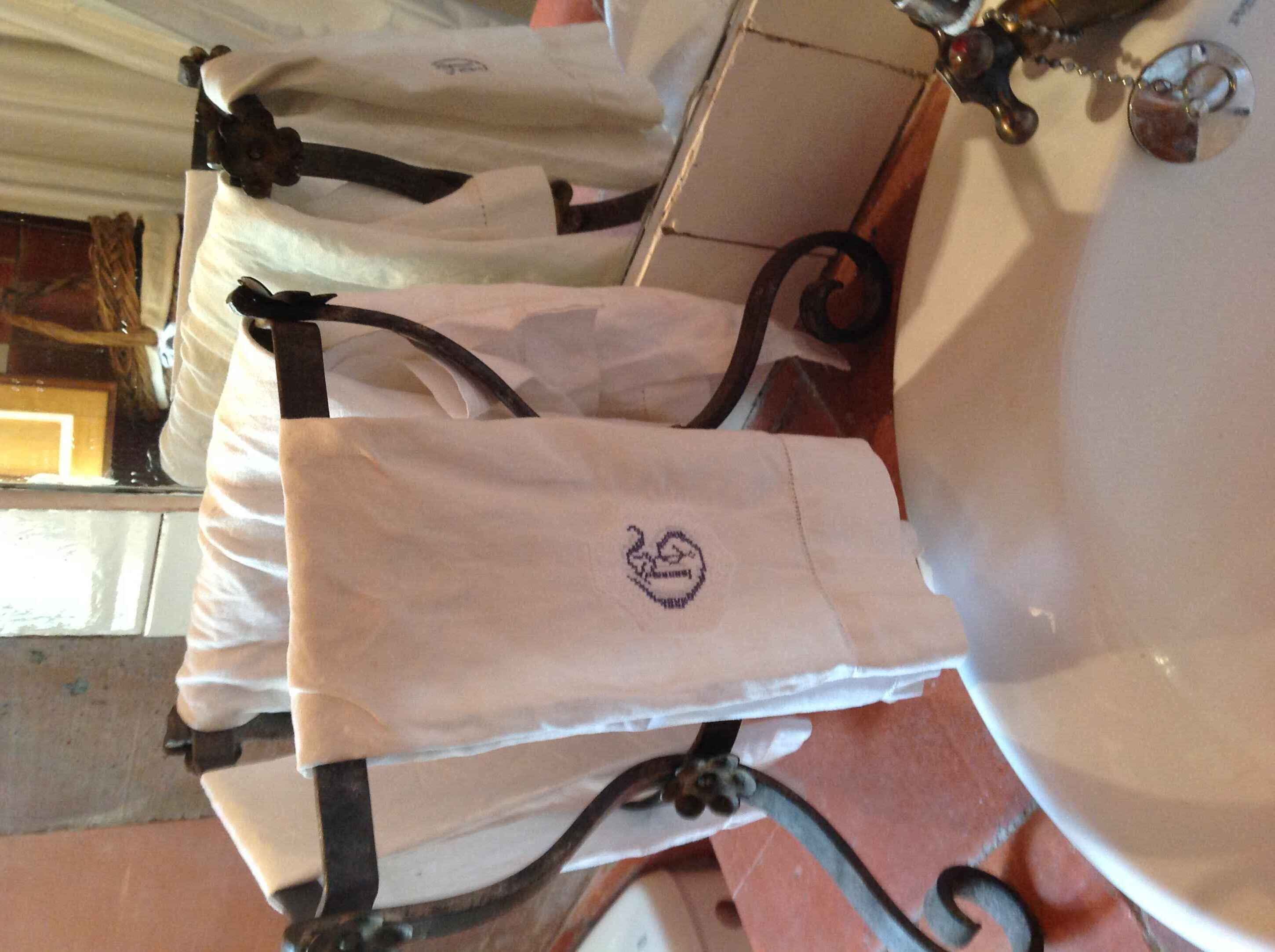 Un bany amb un lavabo blanc, un mirall i un portaTovellons amb diversos tovallons blancs.