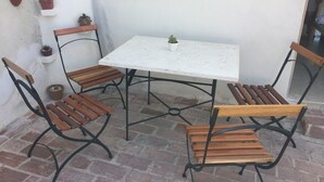 A patio with a white table and four wooden chairs with metal frames. - Casa Boca 170 (Trinidad)