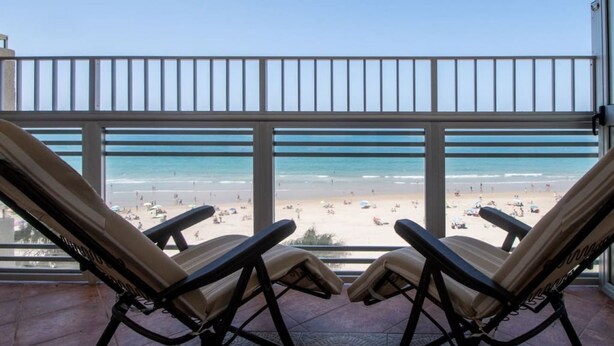 A balcony with two lounge chairs facing a beach. - Apartamento Paseo Maritimo 27 (Cádiz)