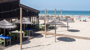 A beachside restaurant with outdoor seating and thatched umbrellas. - Apartamento Paseo Maritimo 27 (Cádiz)