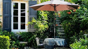 A patio with a table and chairs, a covered umbrella, and a stone staircase. - Gîte La Folie de Labahou (Anduze)