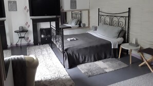 A modern bedroom with a large bed, a television, a small table, and a chair.