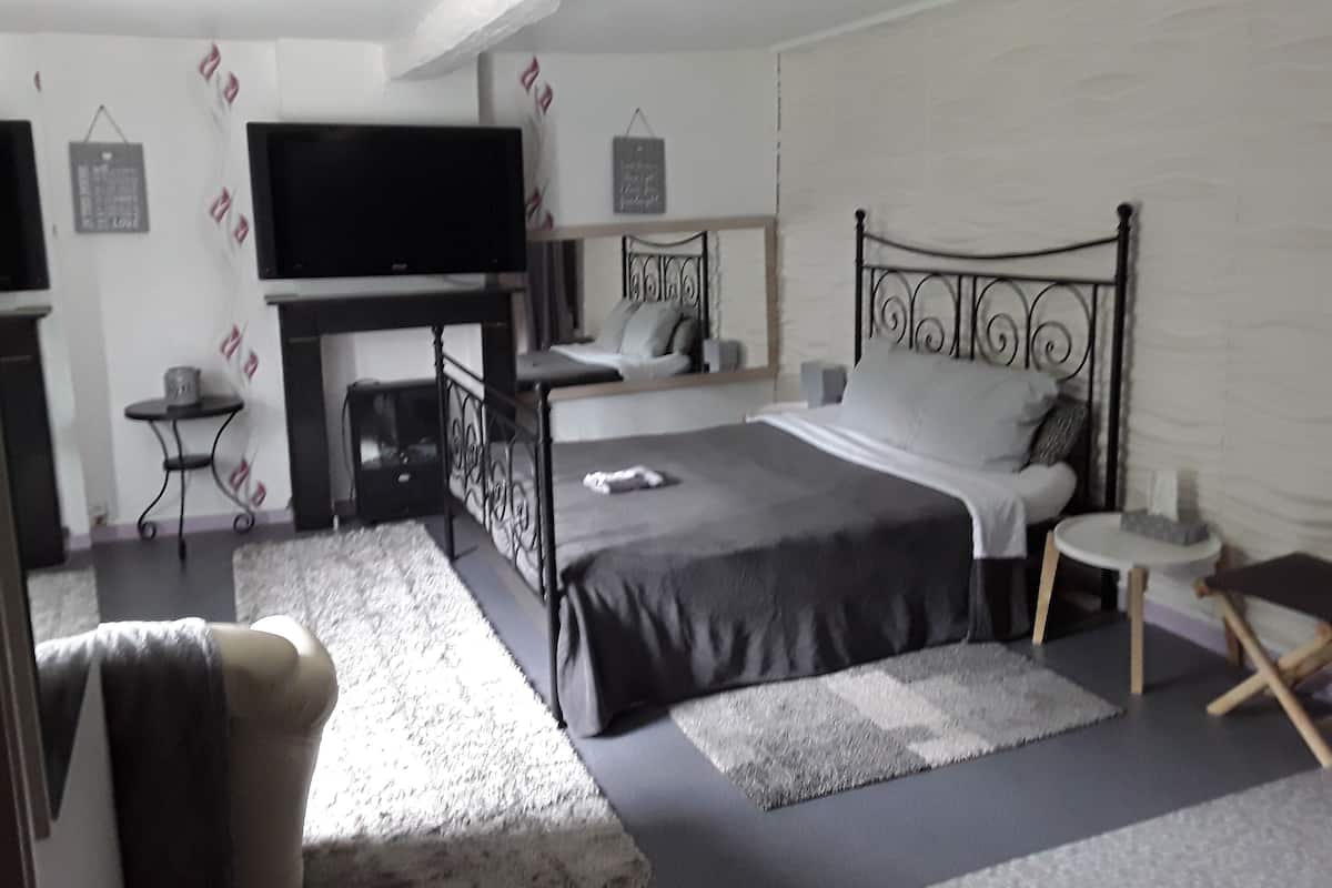A modern bedroom with a large bed, a television, a small table, and a chair.