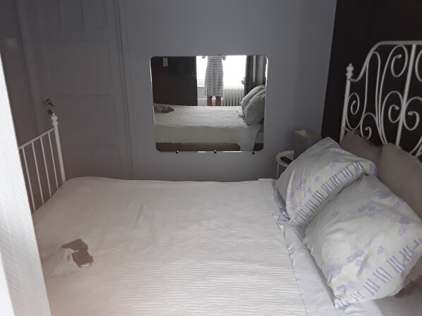 A bedroom with a single bed, a bedside table, a mirror, and a window. - Le Chanteraine (Profondeville)