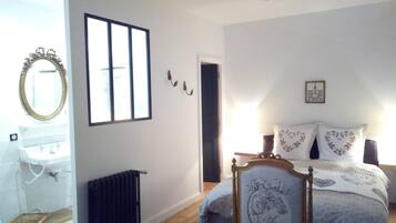 A bedroom with a bed, a radiator, a window, and a mirror.