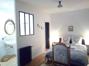 A bedroom with a bed, a radiator, a window, and a mirror.