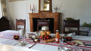 A dining table set with breakfast items, including croissants, fruits, and condiments.