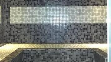 Bathroom features a mosaic tile design, bench, and a rectangular mirror.