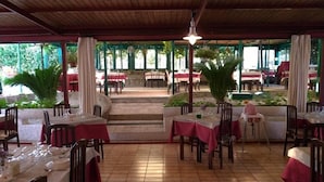 An outdoor restaurant with tables and chairs, covered by a wooden roof, and surrounded by greenery. - Pier delle Vigne B&B (Pineto)