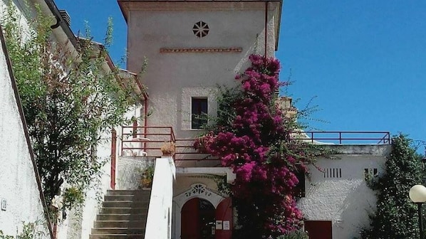 A building with a staircase leading to a door with an arch, a small window, and a decorative element above the door. - Pier delle Vigne B&B (Pineto)