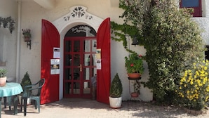 A building entrance with red shutters, a sign reading "Piazza dell'Agroclub," and potted plants. - Pier delle Vigne B&B (Pineto)