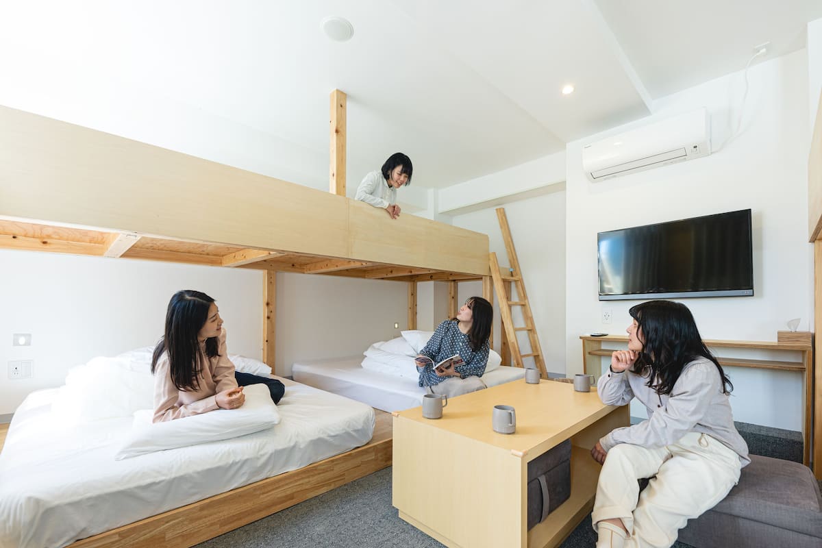 Une chambre de type dortoir, équipée de lits superposés, d’un bureau et d’un téléviseur.