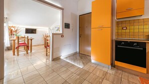 A kitchen with orange cabinets, a black oven, and a tiled floor. - Bed & Breakfast Dorgali (Dorgali)